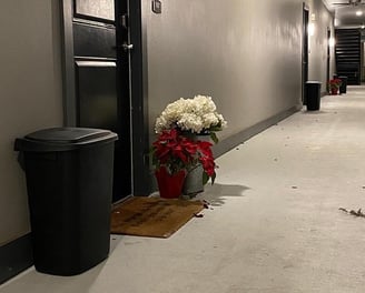 A valet trash bin standing outside of a resident's apartment door.