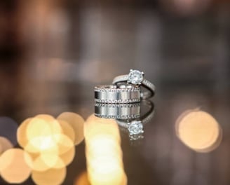 The image captures a stunning wedding ring set displayed on a reflective surface, creating a mirror-