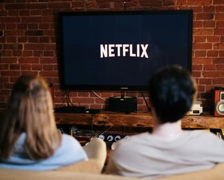 a man and woman sitting on a couch watching a tv