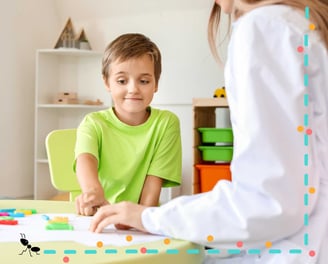 Niño participa en evaluación ADOS-2 infantil con profesional en contexto terapéutico lúdico.