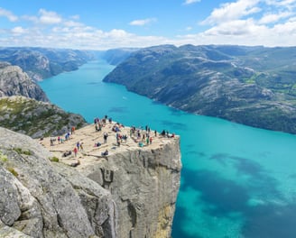 a group of people standing on a cliff overlooking a lake