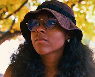 Young college black woman birdwatching underneath golden yellow autumn trees.