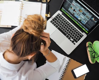 Vista cenital de mujer joven con una laptop, estresada