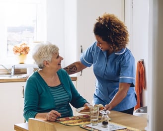 Compassionate caregiver assisting an elderly client with a meal at home, personalized home care