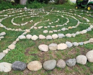 a circular stone labyrinth maze on green grass