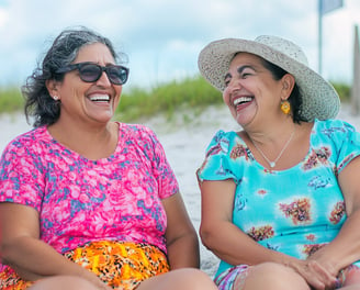 Dos mujeres mayores platicando y riendo en la playa 