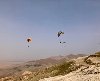 Plusieurs parapentes volent au dessus des dunes du sud du Maroc