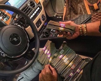 a man sitting in a car with a bunch of money