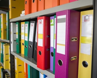 a bunch of folders on a shelf in a library