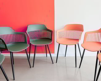 Grey and pink office chairs in a semi circle. Reprensenting facilitation for workshops.