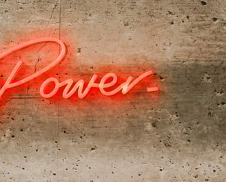 Team Support & Engagement represented by light 'Power' neon on concrete wall. 