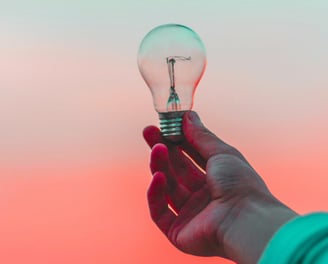 Person holding lighbulb, representing ideas and messaging services.