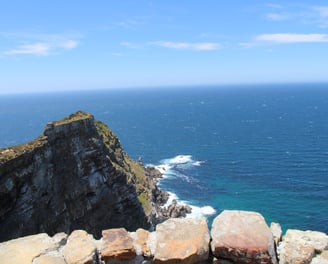 a cliff in front of the ocean, with small waves around the base