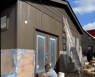 a man is painting a house with a blue sky