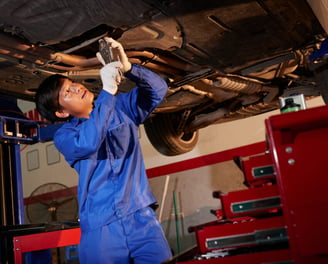 man inspecting under a car