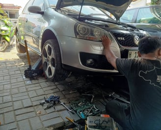 a man working on a VW car with a open hood