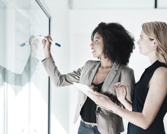 mulheres do mundo corporativo escrevendo em quadro
