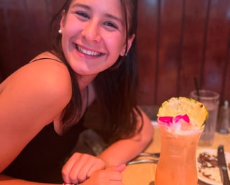 A girl sitting a table drinking a drink