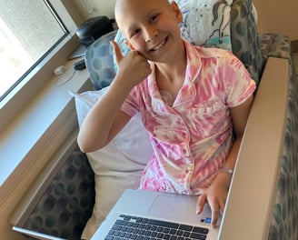 A girl who is fighting cancers giving a thumbs up.