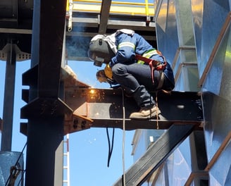 a man in a helmet welding a metal structure