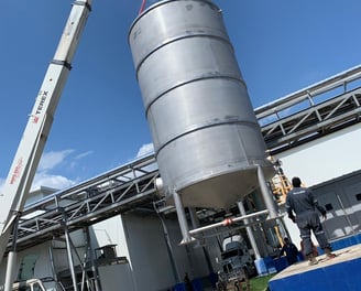 a crane lifts a large metal tank into place