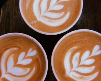 three cups of coffee with a leaf design on the bottom