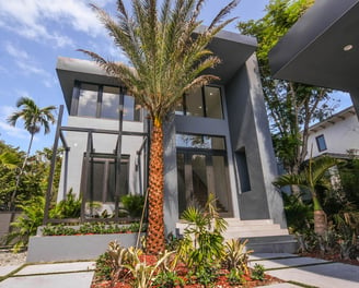 Modern Modular shaped house with palm trees and a gate and walkway