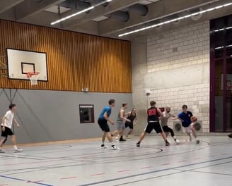 alt="Jugendliches Basketballteam beim Training auf dem Feld."