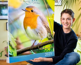 Philipp Geisler präsentiert seinen großen Fotokalender mit Vogelmotiven in seinem Zimmer