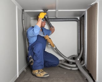 A circular ventilation duct is embedded in a white wall, featuring a series of concentric rings inside the vent. The surrounding area is clean and minimalistic with an overall bright appearance.