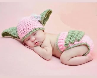 a baby yoshi is wearing a pink and green hat
