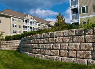 a wall of stone with a clock tower in the background