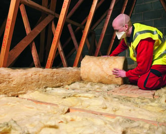 a man in a yellow vest and safety vest is working on a roof