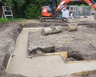 Groundwork contractor laying concrete foundation