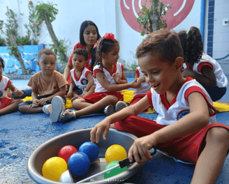 Crianças da educação infantil sentadas realizando atividades lúdicas