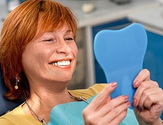 Smiling woman looking her smiling face in a mirror