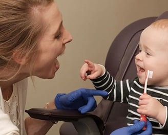 Child holding tooth brush with dentist