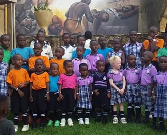 a group of children and adults standing in front of a large painting of a painting