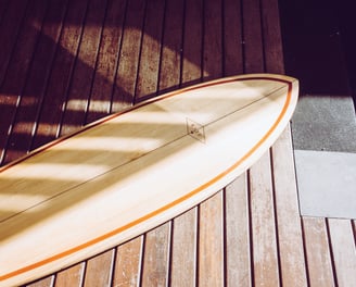 Handmade balsa surfboard resting on a wooden deck