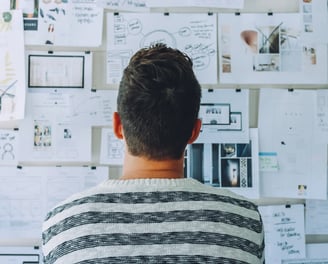 a man standing in front of a wall of papers and papers