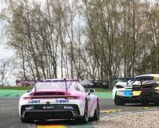 Porsche 911 gt3 rosa e bianca in curva durante gara