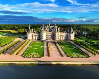 a castle like building with a large lawn and a lake