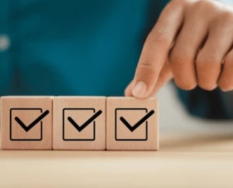 Close-up of hand placing a checklist block, representing quality control in product sourcing and ins