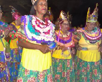 Ciganinhas dançando com roupas floridas e coroas, celebrando cultura e resistência quilombola