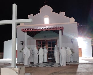 Penitentes de branco em frente à capela, em ritual noturno de fé e arrependimento em São Tomé