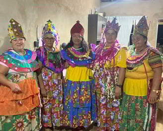 Ciganinhas com roupas coloridas, coroas e saias longas em ambiente interno, prontas para dançar
