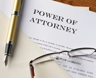 Power of attorney document with pen and glasses, symbolizing legal financial authority.