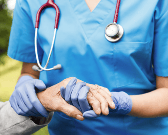 Nurse holding elderly hand, symbolizing compassionate medical decisions in estate planning.