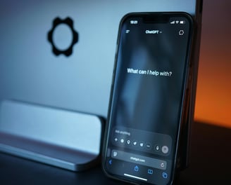 a phone in front of a laptop with ChatGPT on the screen