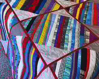colorful quilt with red sashes and multicolored strips made for my son